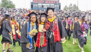 A group of students at a graduation ceremony wearing layered custom stoles and regalia items.